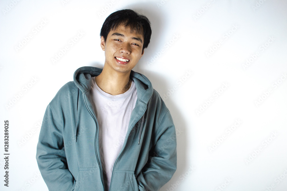 Asian teenager in white t-shirt and blue hoodie, smiling sweetly Asian teenager in white t-shirt and blue hoodie, smiling sweetly