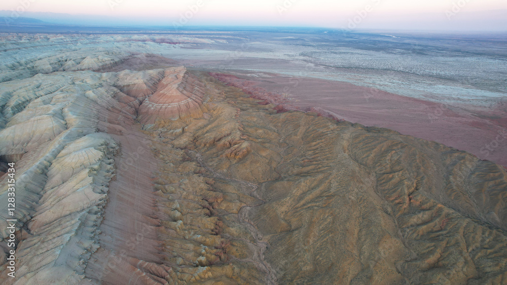 Capturing an aerial view of colorful mountains and hills merging with a pink desert at sunset in mangystau, kazakhstan, reveals a breathtaking landscape of untouched wilderness