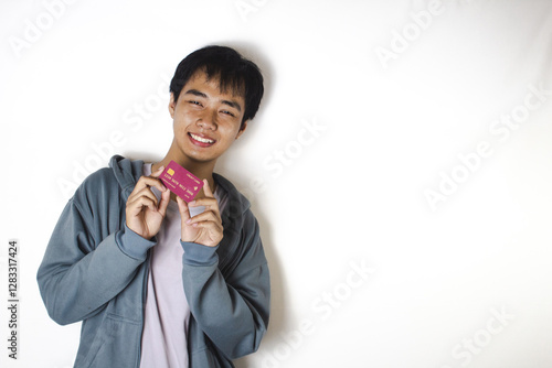 Asian teenager in white t-shirt and blue hoodie, posing holding his credit card