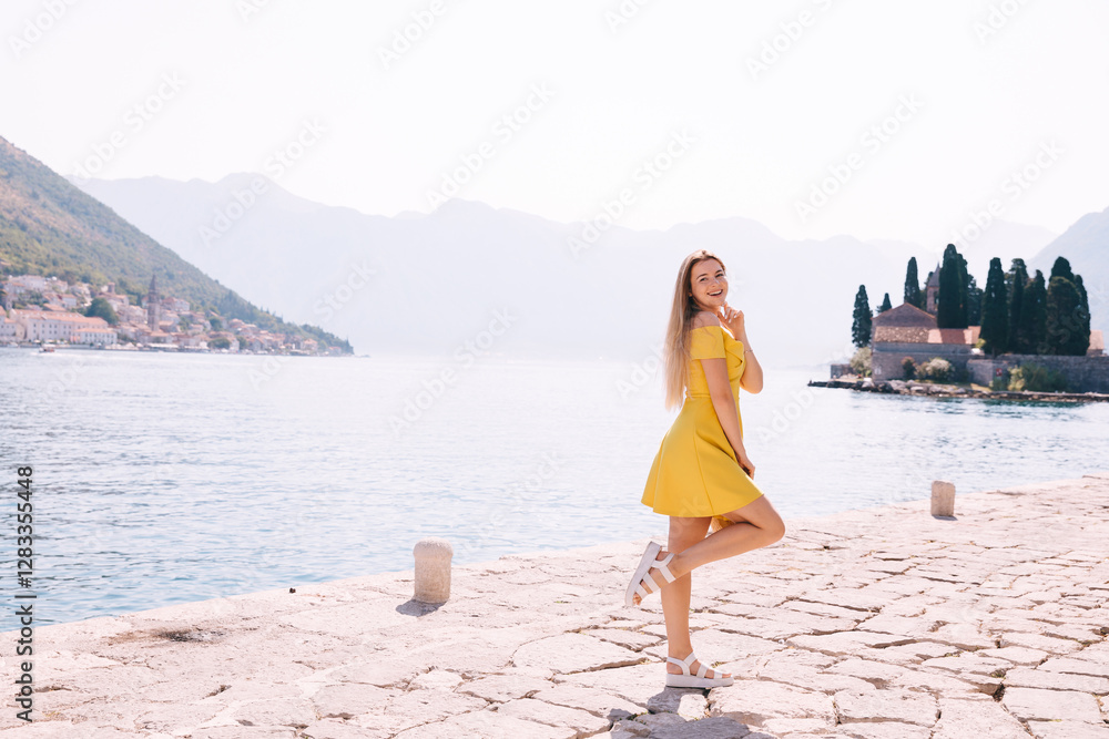 Woman in yellow dress enjoying scenic seaside view on a sunny day Woman in yellow dress enjoying scenic seaside view on a sunny day