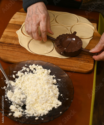 Obraz na płótnie Woman skillfully fills dough circles with cheese in a warm kitchen w salonie