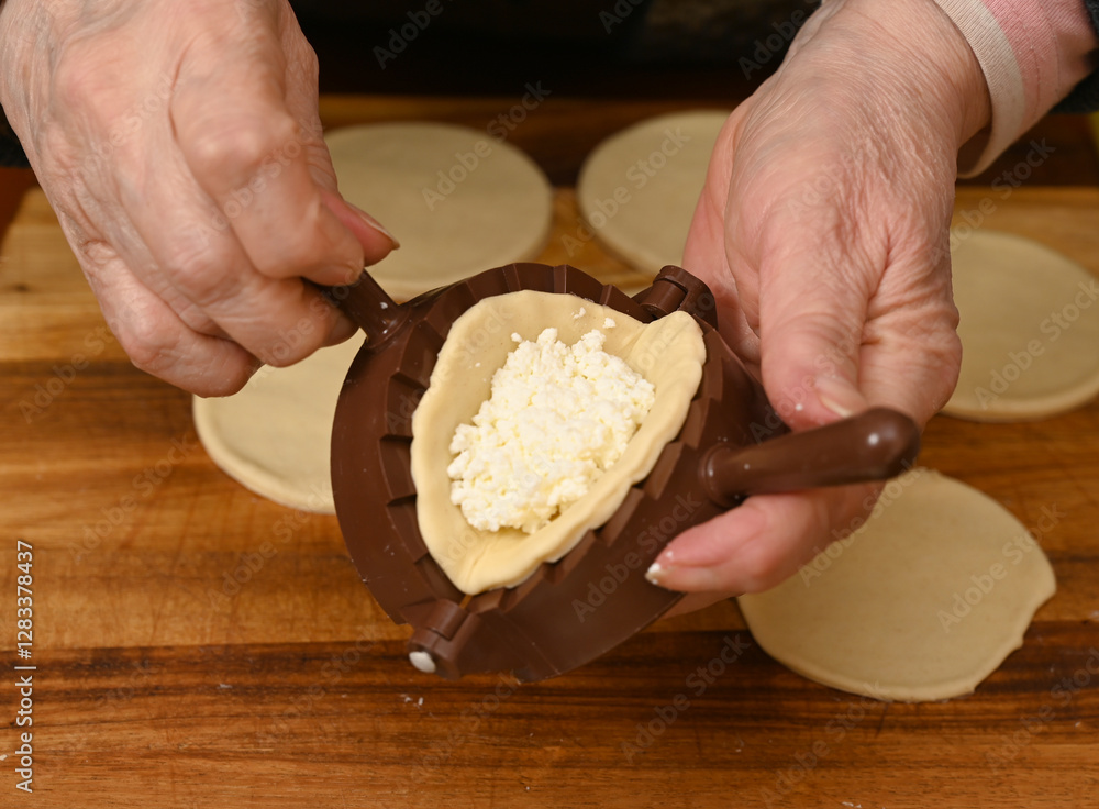 Woman skillfully fills dough circles with cheese in a warm kitchen.