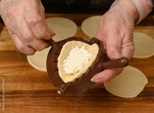 Woman skillfully fills dough circles with cheese in a warm kitchen.