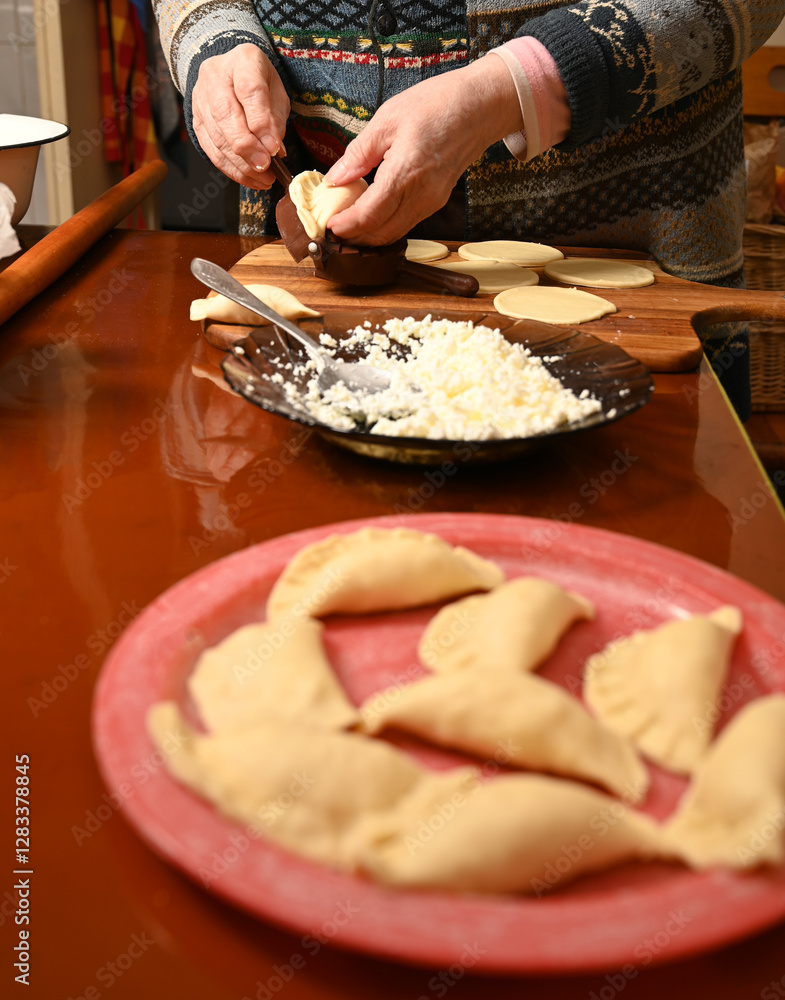 Woman skillfully fills dough circles with cheese in a warm kitchen.