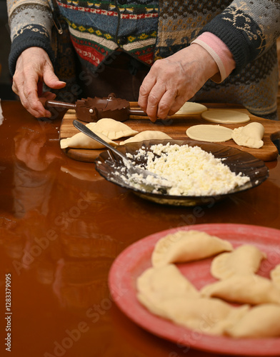 Obraz na płótnie Woman skillfully fills dough circles with cheese in a warm kitchen w salonie