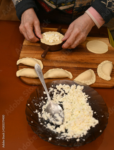 Obraz na płótnie Woman skillfully fills dough circles with cheese in a warm kitchen w salonie