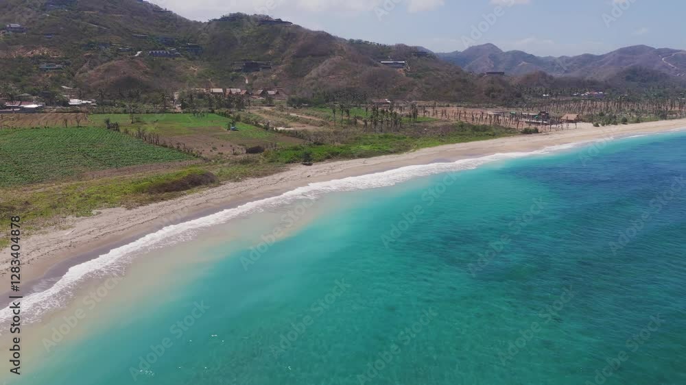 Sandy beach with turquoise waters and green fields in Lombok, Indonesia Sandy beach with turquoise waters and green fields in Lombok, Indonesia