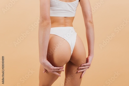 Foto Woman in white underwear touching her buttocks posing on beige background