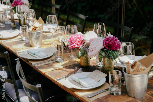 Tablou pe pânză Elegant outdoor dining setup adorned with flowers and glassware in a serene gard