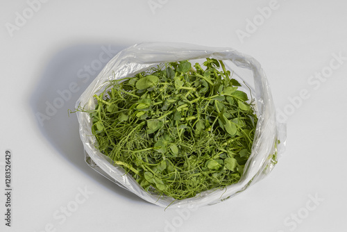 cut pea microgreens weighing 50 grams placed in a plastic bag and prepared for storage on a gray background
