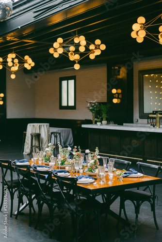Elegant dining setup in a modern venue with decorative lighting and floral accents for a special occasion
