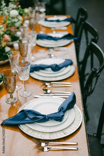 Elegant table setting with fine dining utensils and blue napkins in a beautifully arranged venue