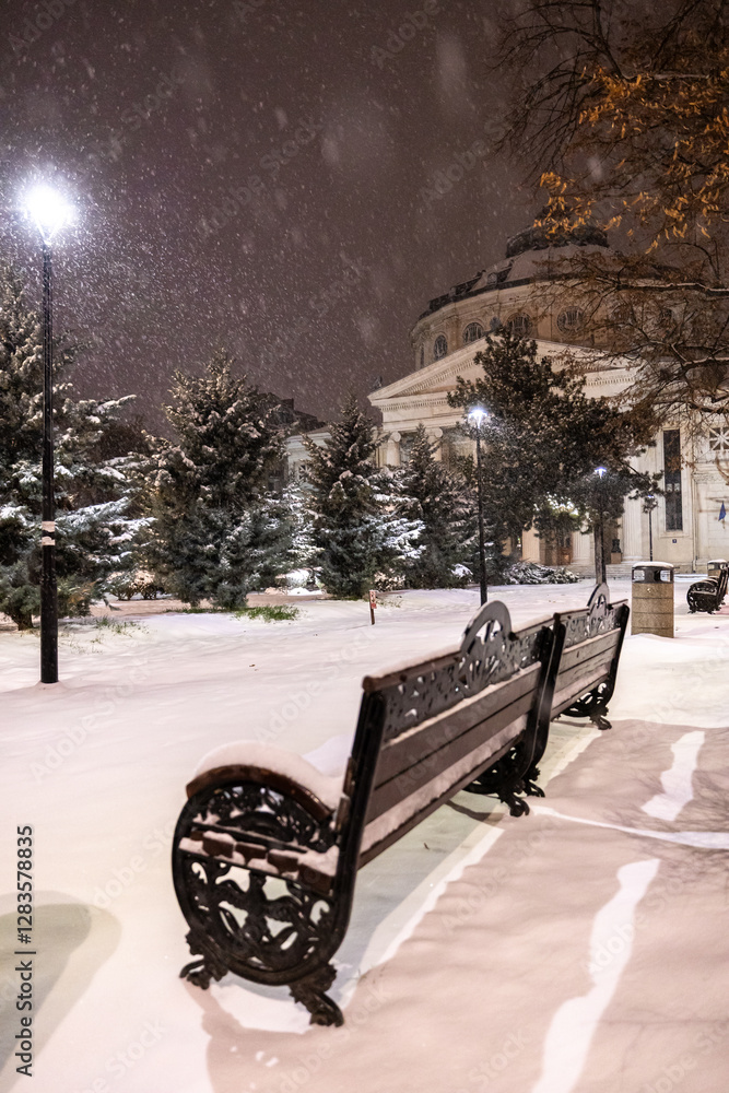 Winter in Bucharest. The Romanian Athenaeum covered in fresh snow at night, with snowfall adding a magical winter atmosphere to the historic landmark in Bucharest.