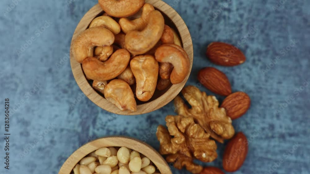 Close-up of cashews and pine nuts in wooden bowls, almonds and walnuts lie next to them, smooth camera movement. The concept of vitamins, the use of nuts, products with nuts. High quality 4k footage Close-up of cashews and pine nuts in wooden bowls, almonds and walnuts lie next to them, smooth camera movement. The concept of vitamins, the use of nuts, products with nuts. High quality 4k footage