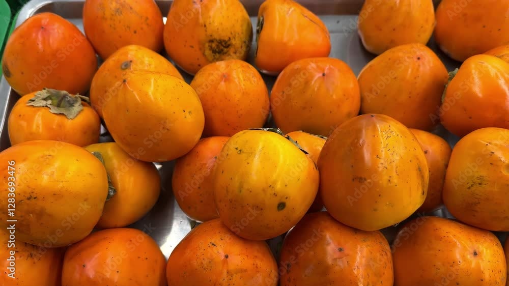 Fresh ripe persimmons of bright color on the counter in boxes Fresh ripe persimmons of bright color on the counter in boxes