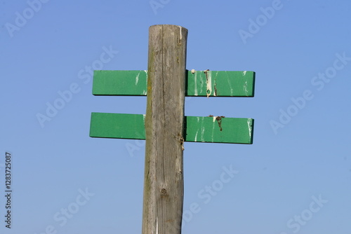 Weathered Wooden Signpost with Blank Green Direction Signs Against Blue Sky