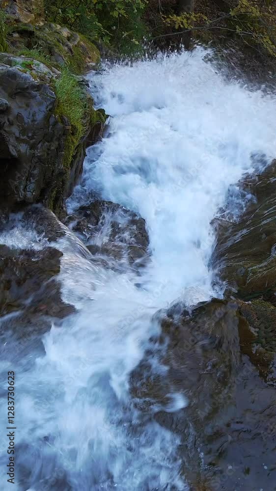 A gentle mountain stream is flowing peacefully over rocks and lush greenery around it A gentle mountain stream is flowing peacefully over rocks and lush greenery around it