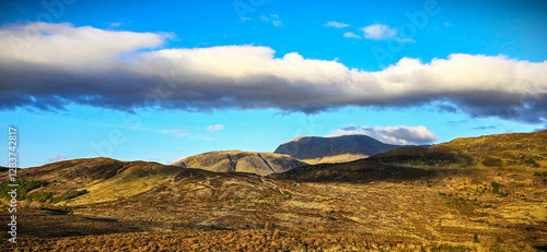 Golden hills and towering peaks beneath a sky painted with clouds—nature’s masterpiece on full display. A moment to pause, breathe, and admire the wild beauty of the highlands photo