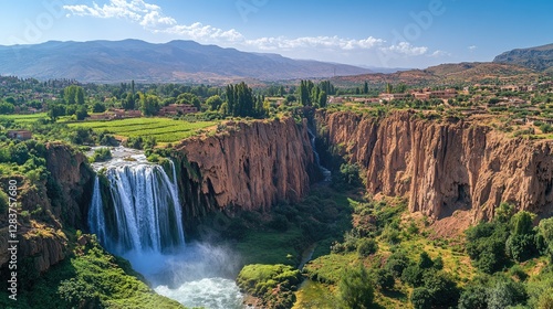 Majestic waterfall cascades down cliffs, village backdrop, sunny day, travel photography