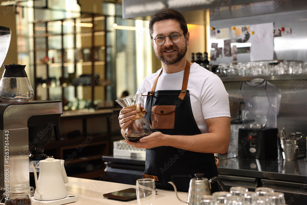 Barista with glass coffeemaker at table in cafe Barista with glass coffeemaker at table in cafe
