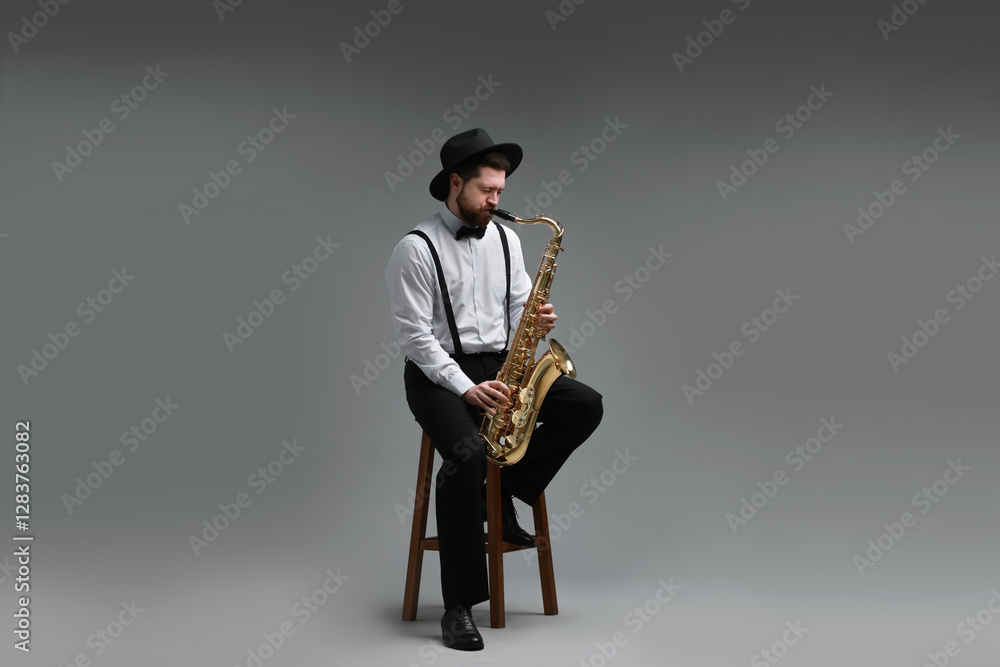 Naklejka premium Professional musician playing saxophone on grey background