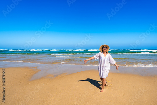 Happy middle-aged woman tourist enjoying sun and beautiful sandy beach on Armona island, Portugal. Front view	 photo