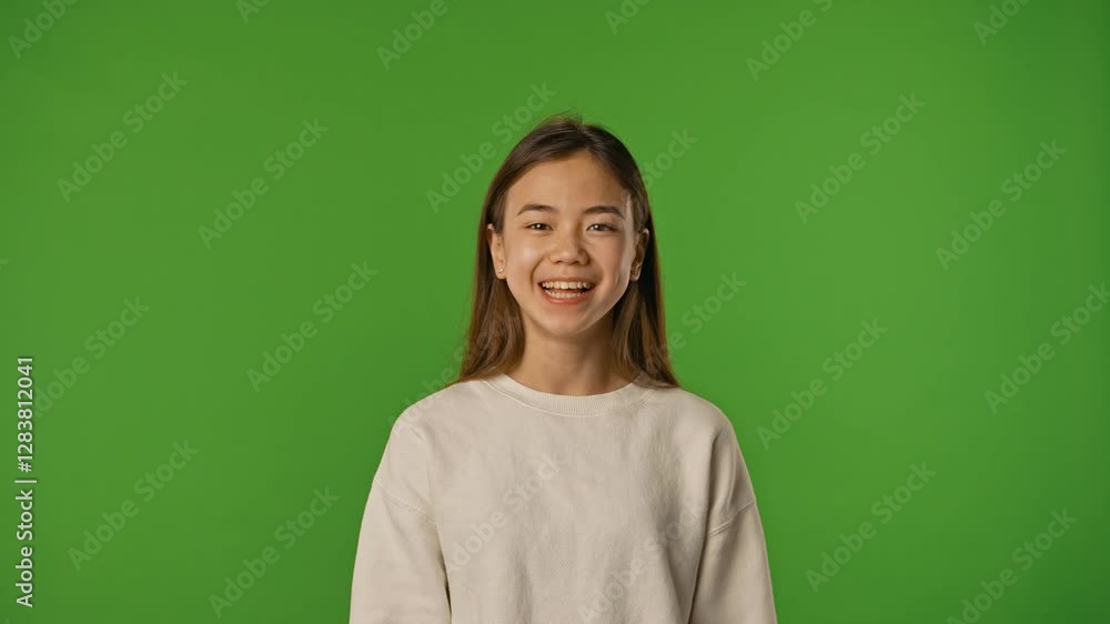 Asian girl child makes grimaces funny faces, poses and sticks out tongue, positive expression, isolated on chroma key green screen studio background mockup. Asian girl child makes grimaces funny faces, poses and sticks out tongue, positive expression, isolated on chroma key green screen studio background mockup.