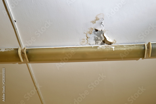 Foto Damaged ceiling with water stains and peeling paint near fluorescent light fixture