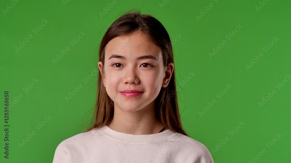 Asian girl child in shirt standing looking at camera and smiling, positive expression, isolated on chroma key green screen studio background mockup. Asian girl child in shirt standing looking at camera and smiling, positive expression, isolated on chroma key green screen studio background mockup.