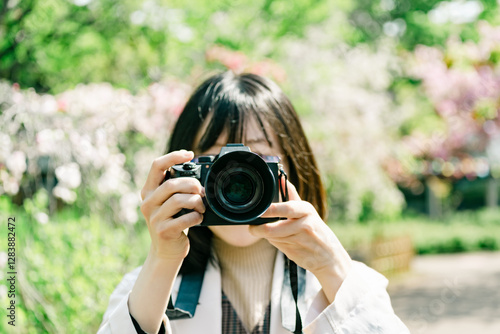 公園の花を一眼レフで撮る女性