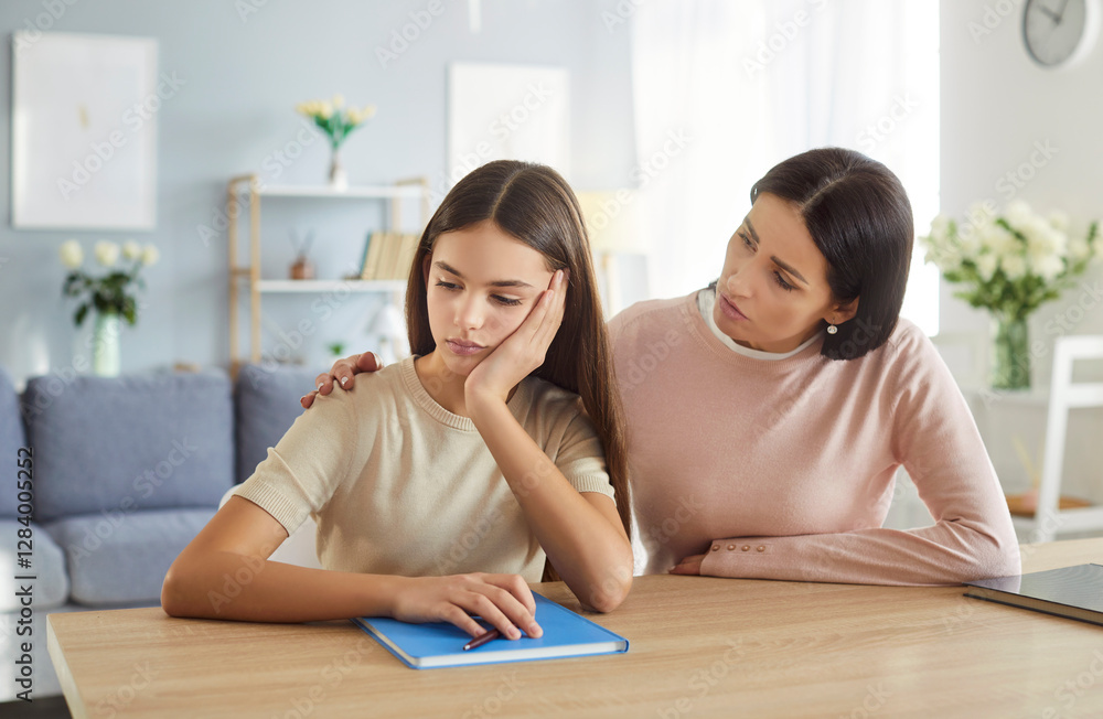 Portrait of young mother parent talking and support her teenage upset child girl tired of doing school homework sitting at the desk in living room at home. Education and knowledge concept. Portrait of young mother parent talking and support her teenage upset child girl tired of doing school homework sitting at the desk in living room at home. Education and knowledge concept.