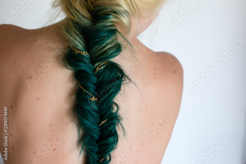 Close-up of a green fishtail braid with gold accents on bare back