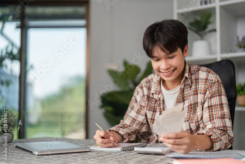 Fotografi Teenager managing finances at home, reviewing bills and budgeting with a smile