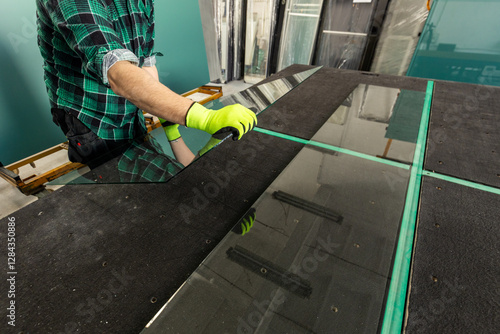 Obraz na płótnie Work in a glass factory. A glazier places a sheet of glass on a specialized table. Close up w salonie