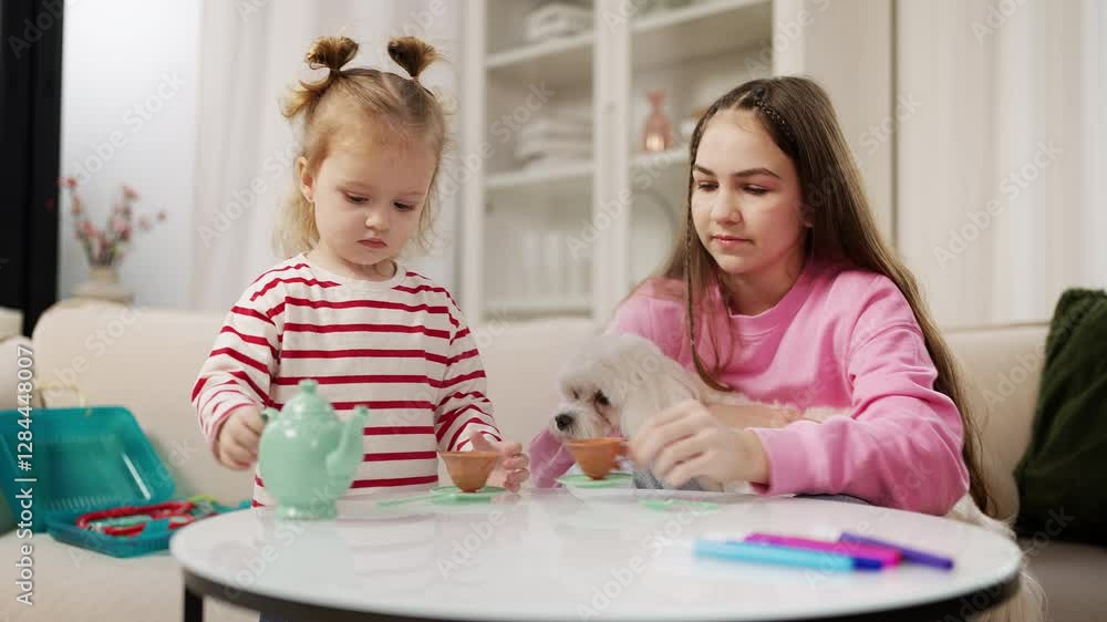 Little girl and her elder sister play a tea party together with their puppy Little girl and her elder sister play a tea party together with their puppy