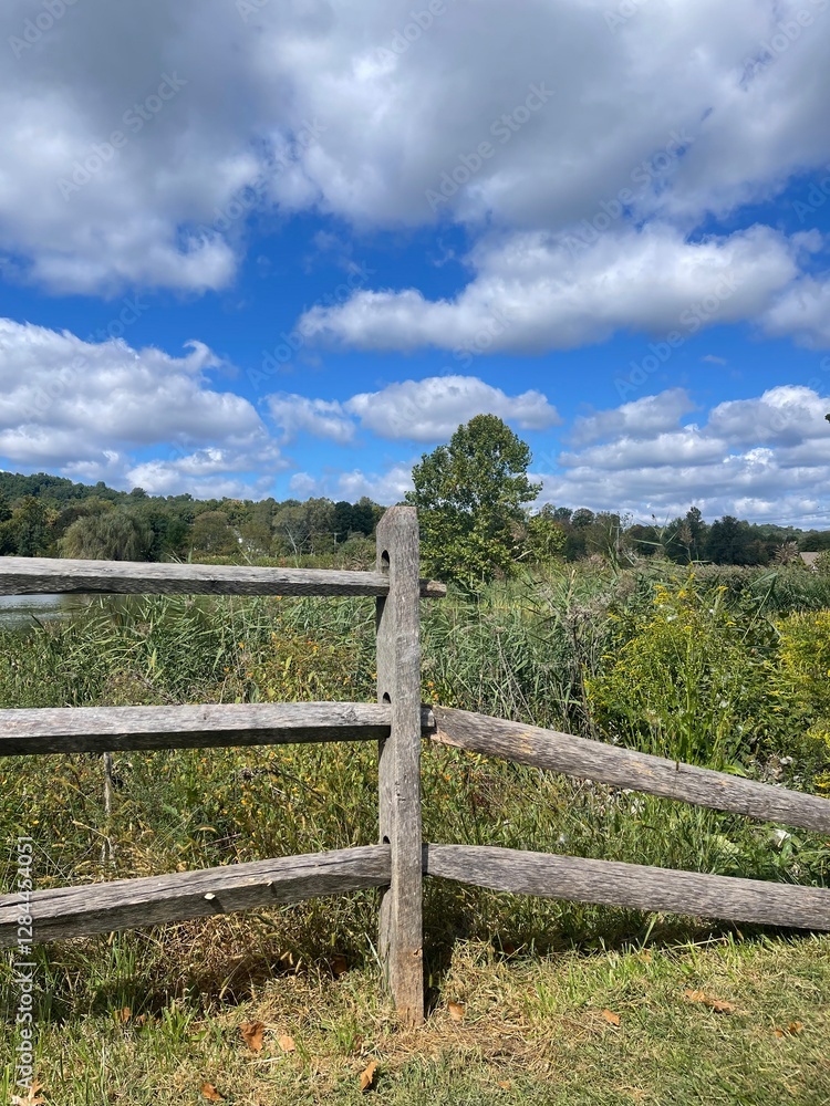 Old Weathered Split Rail Cedar Wood Fence, next to a Pond and a Grassy Meadow Field. Old Weathered Split Rail Cedar Wood Fence, next to a Pond and a Grassy Meadow Field.