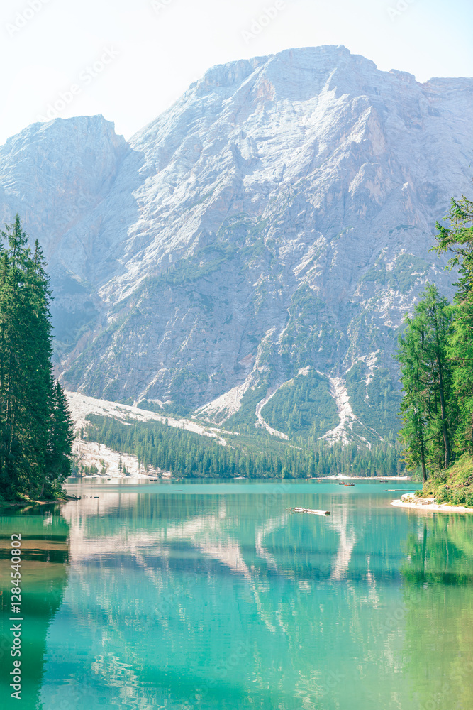 Stunning Alpine lake Pragser Wildsee located in the Dolomites of South Tyrol, Italy. Turquoise water of lake reflects towering, rugged mountains and lush green trees surrounding it