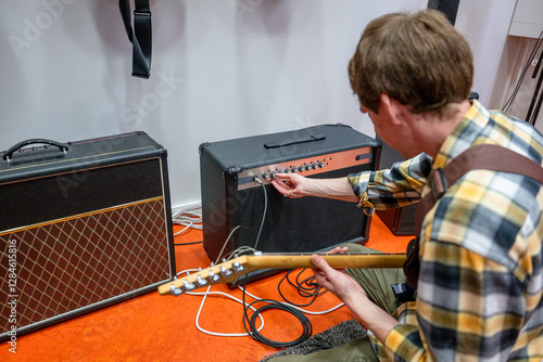Guitarist adjusting settings on amplifier of electric guitar in the music studio