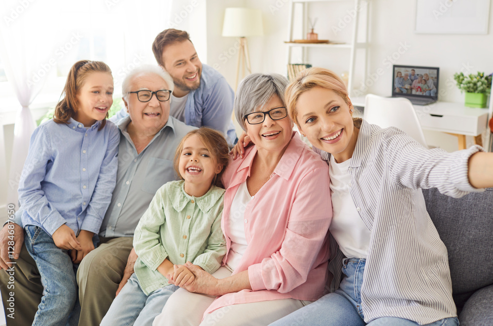 Happy family, three generation people, senior parents with adorable adult children, little kids having fun, smiling holding smartphone, taking common selfie, overjoyed sitting on cozy couch at home Happy family, three generation people, senior parents with adorable adult children, little kids having fun, smiling holding smartphone, taking common selfie, overjoyed sitting on cozy couch at home