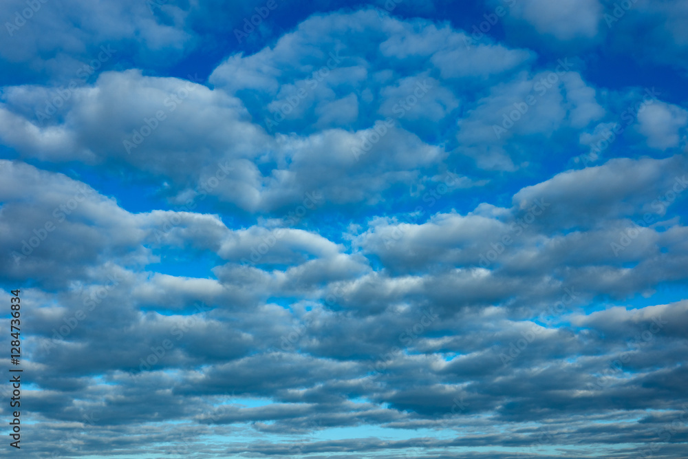 Blue sky and lot of small clouds in middle of sunny day. No horizon is visible.