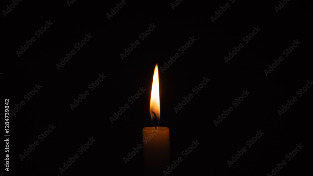 A burning candle on a black background A burning candle on a black background