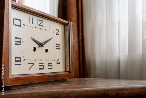A table clock with a chime, Roman numerals and a wooden case.Vintage apartment design in the classic style of the 60s. Veneered furniture in the interior.