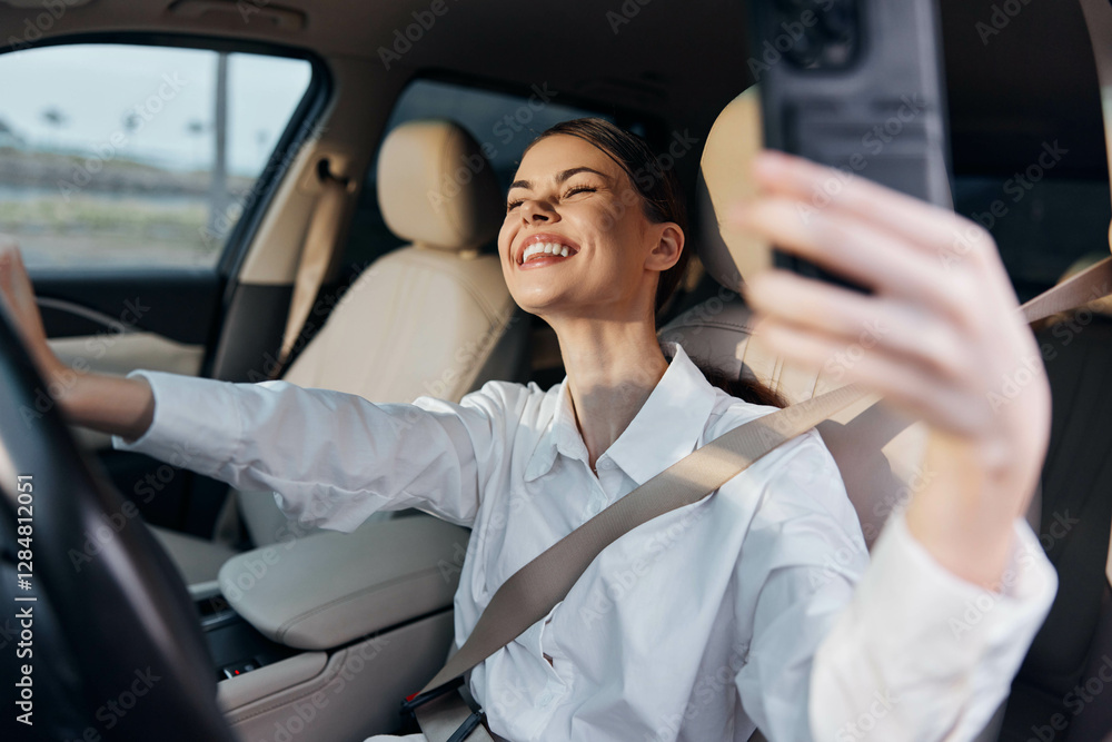 Woman taking selfie in car a smiling woman sits in the driver's seat of a vehicle, holding a smartphone to capture a selfie while looking at the camera