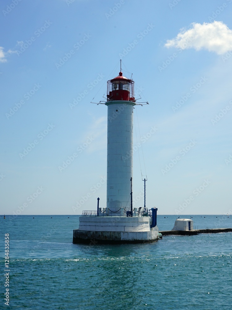 A tall lighthouse stands prominently on a quaint small island in the vast ocean A tall lighthouse stands prominently on a quaint small island in the vast ocean