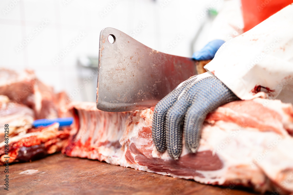 Food processing factory. Meat industry. Close up view of butcher using cleaver to cut pork meat. Food processing factory. Meat industry. Close up view of butcher using cleaver to cut pork meat.