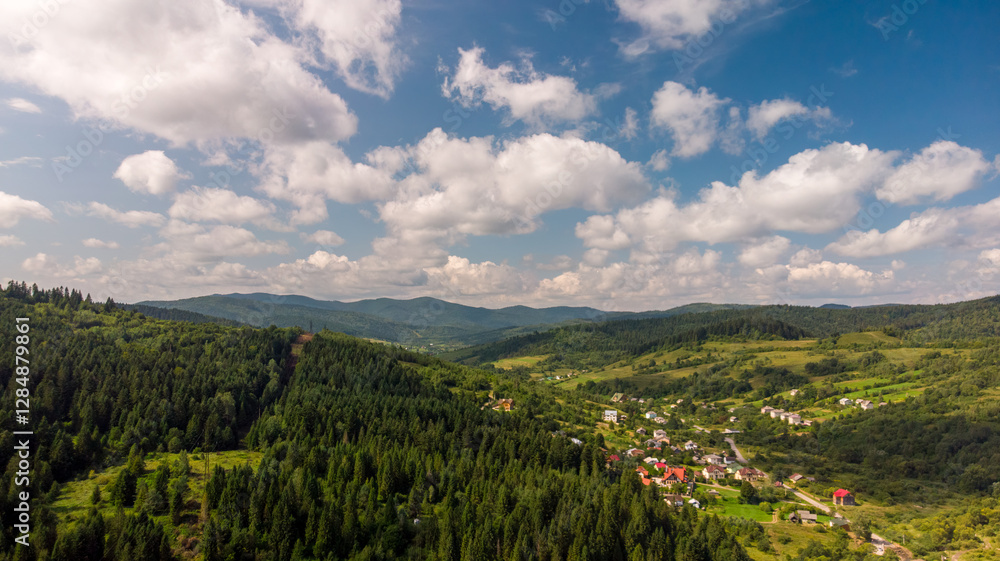Fototapeta premium Majestic Mountains, Lush Green Forests, And Soft White Clouds On A Sunny Day. Aerial View Showcasing The Stunning Beauty Of Nature From A High Perspective.