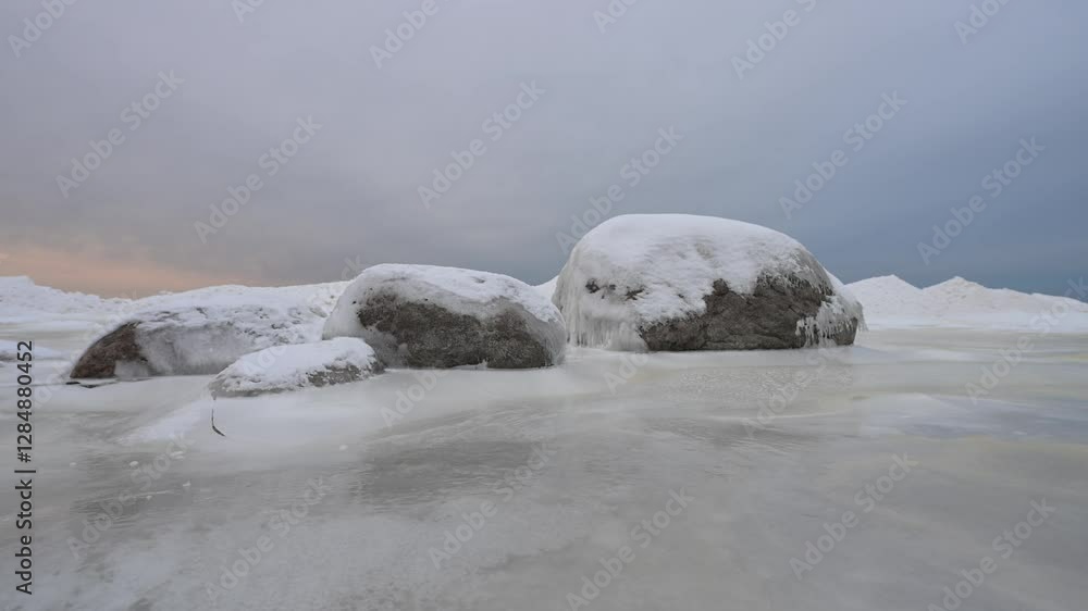 Snenic icy seashore with a boulders covered in ice and snow at sunset. Snenic icy seashore with a boulders covered in ice and snow at sunset.