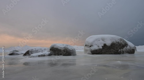 Snenic icy seashore with a boulders covered in ice and snow at sunset. photo