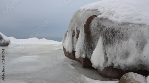 Snenic icy seashore with a boulder covered in ice and snow. photo