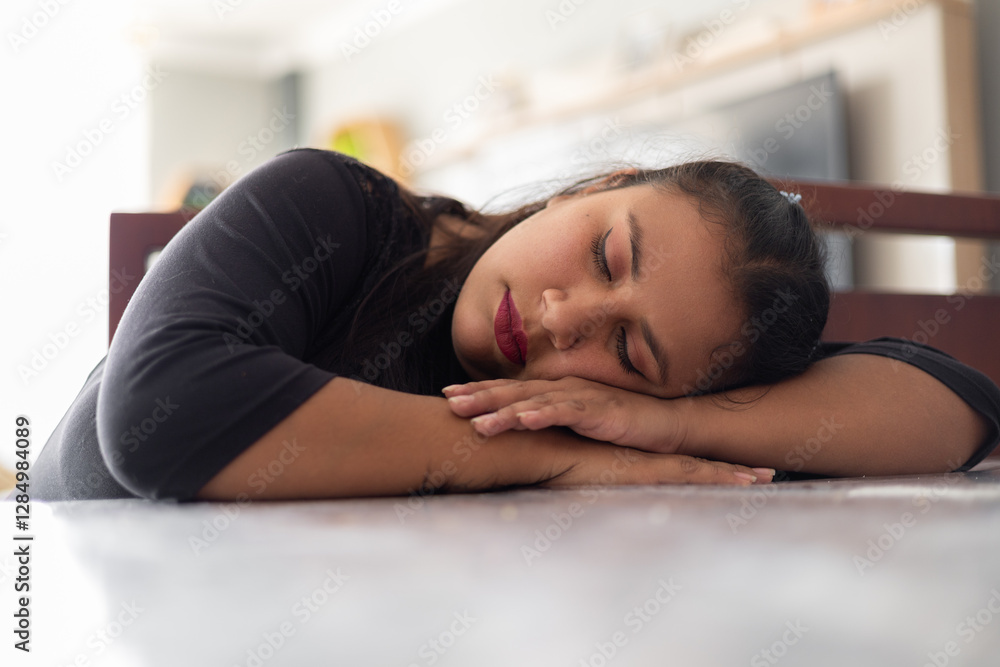A young person sleeping on the dining table, ideal for content about rest, exhaustion, and everyday life. A young person sleeping on the dining table, ideal for content about rest, exhaustion, and everyday life.